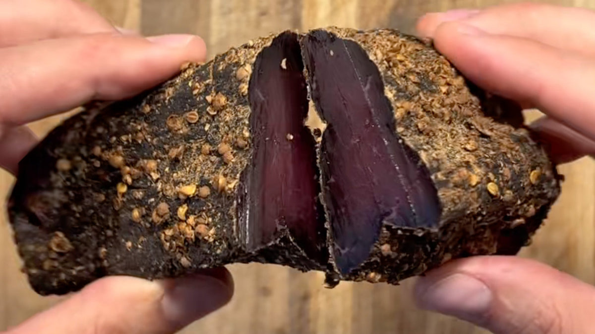 Sliced homemade biltong on a wooden board, dried on a Meatdryer hook