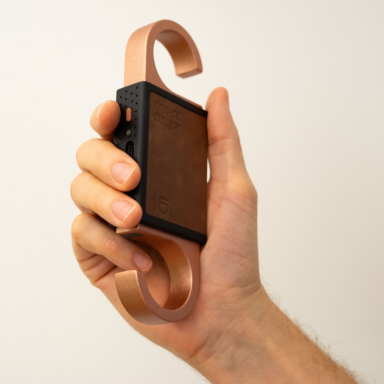 Hand holding a smart meet hook against a plain background